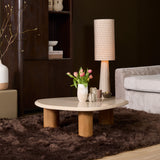 Ronde salontafel met licht marmeren blad en houten poot in woonkamer, met bloemenvaas