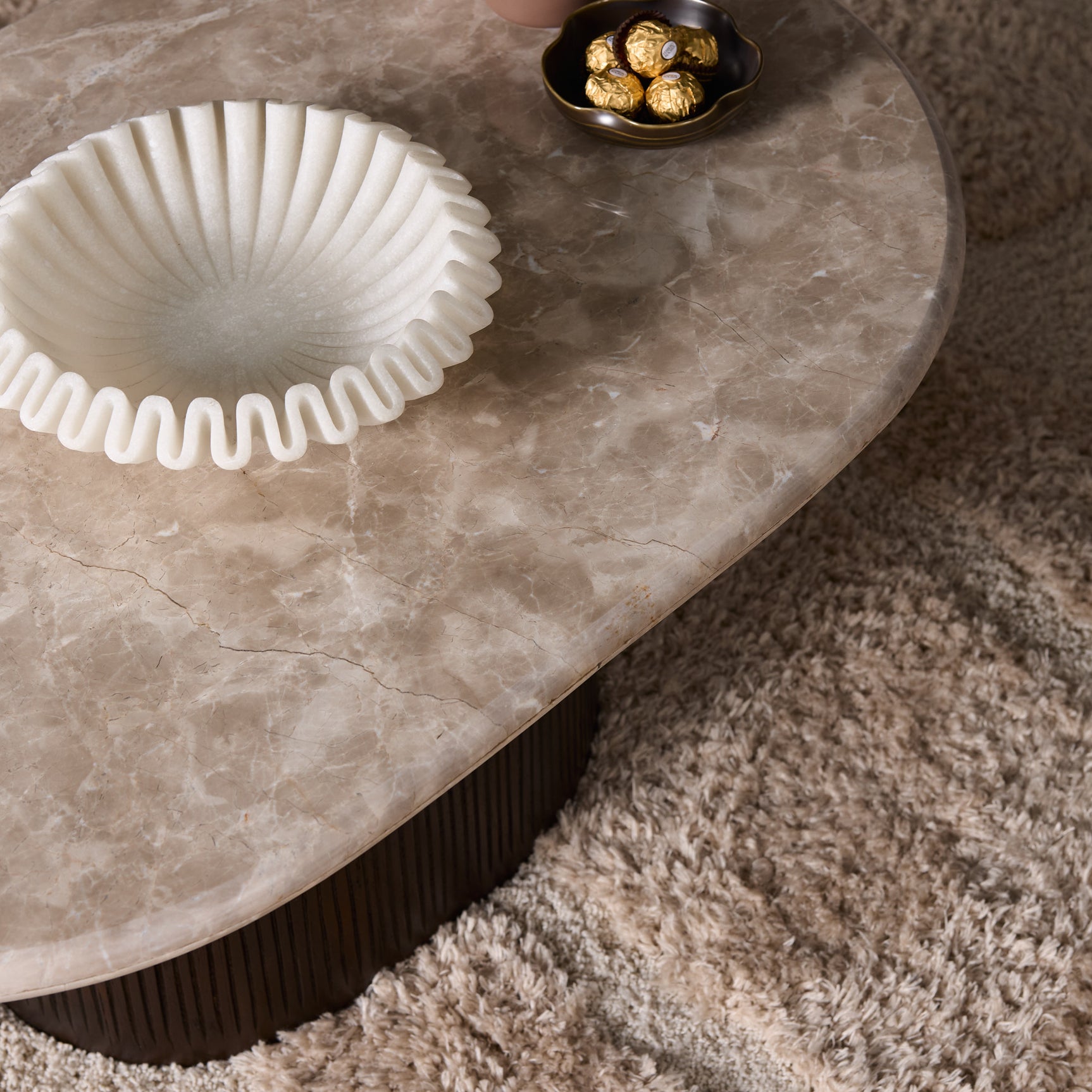 Ronde salontafel met licht marmeren blad en donker geribbelde poot