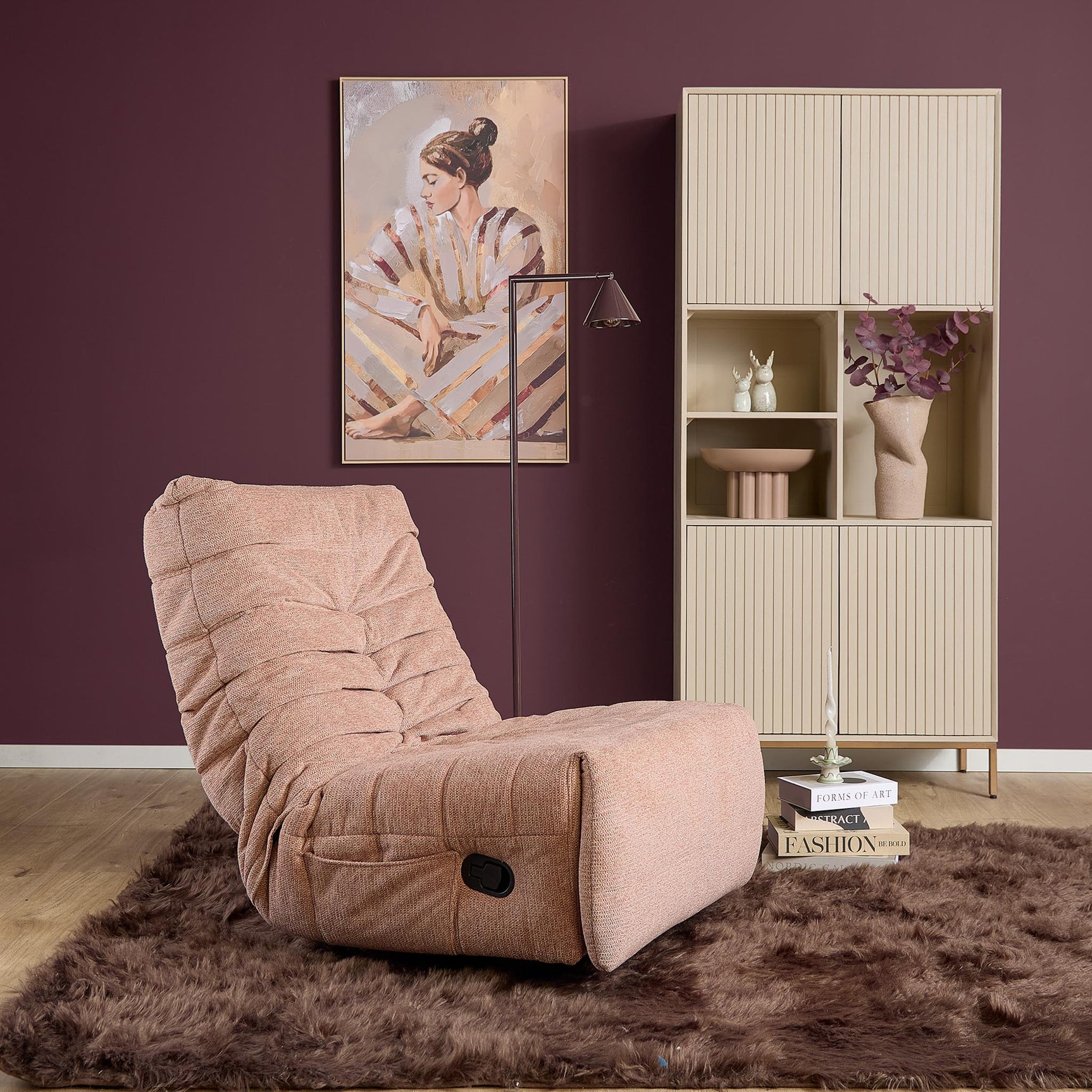 Roze relaxfauteuil met opklapbare voetensteun en zwarte bediening op de armleuning.