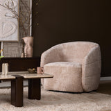 Beige gestoffeerde fauteuil met ronde rug en armleuningen, dikke zitting en organische vorm.