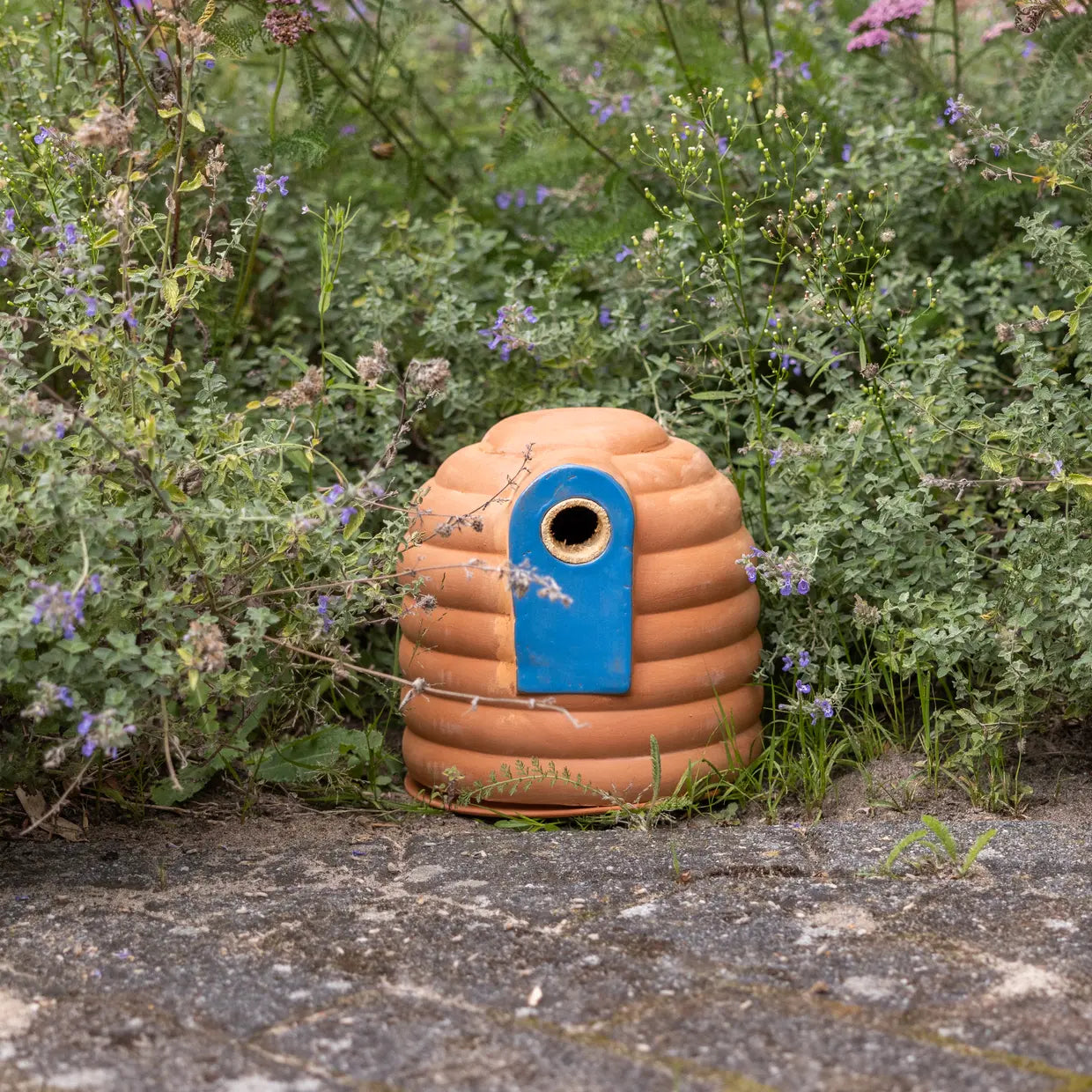 Terracotta hommelpot met blauwe omlijsting en ronde zwarte opening