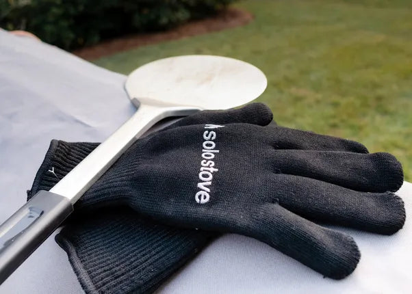 Pizza draaier uit rvs op zwarte ovenhandschoenen met witte schep