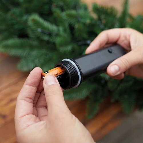 Snoer met LED-lampjes en zwarte aansluitdop, vastgehouden door handen