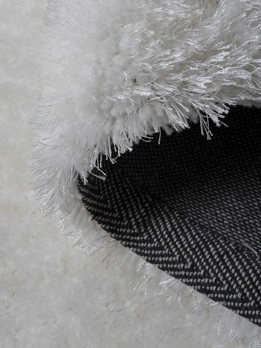 Wit harig karpet met gekruiste franjes en donkere onderrand