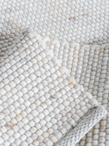 Vloerkleed close-up: lichte beige geweven structuur met lussen en pool