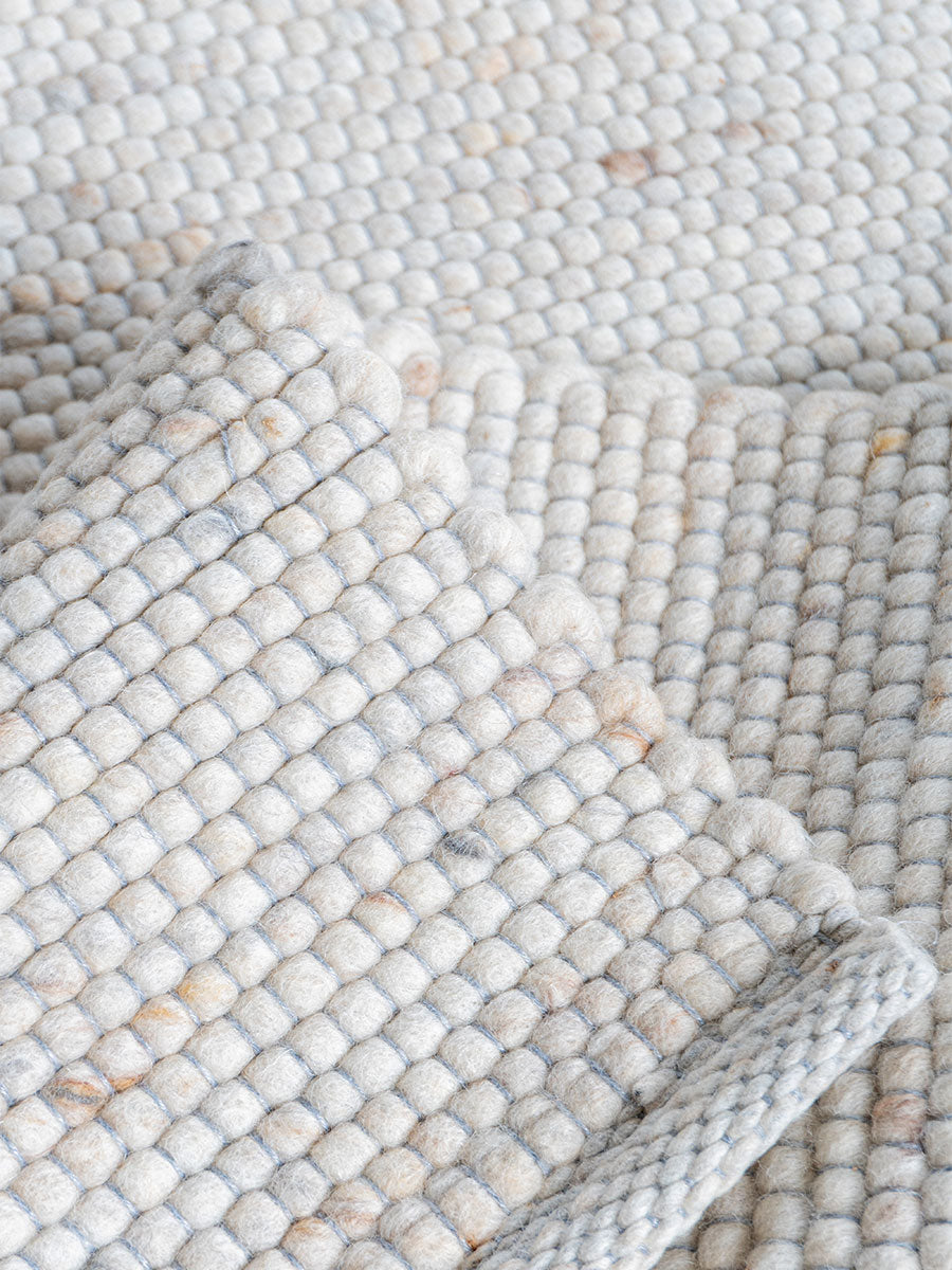Vloerkleed close-up: lichte beige geweven structuur met lussen en pool